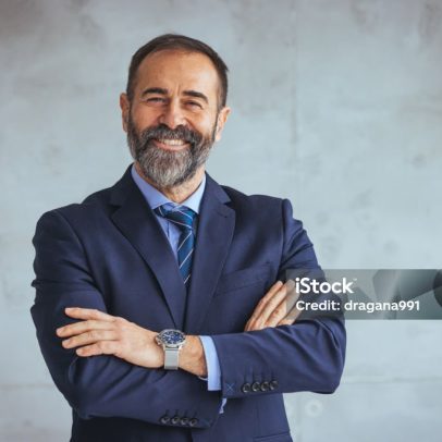 Cropped shot of executive Mature businessman wearing suit and tie while standing at isolated grey background. Copy space. Businessman looking at the camera while standing alone in a modern workplace.